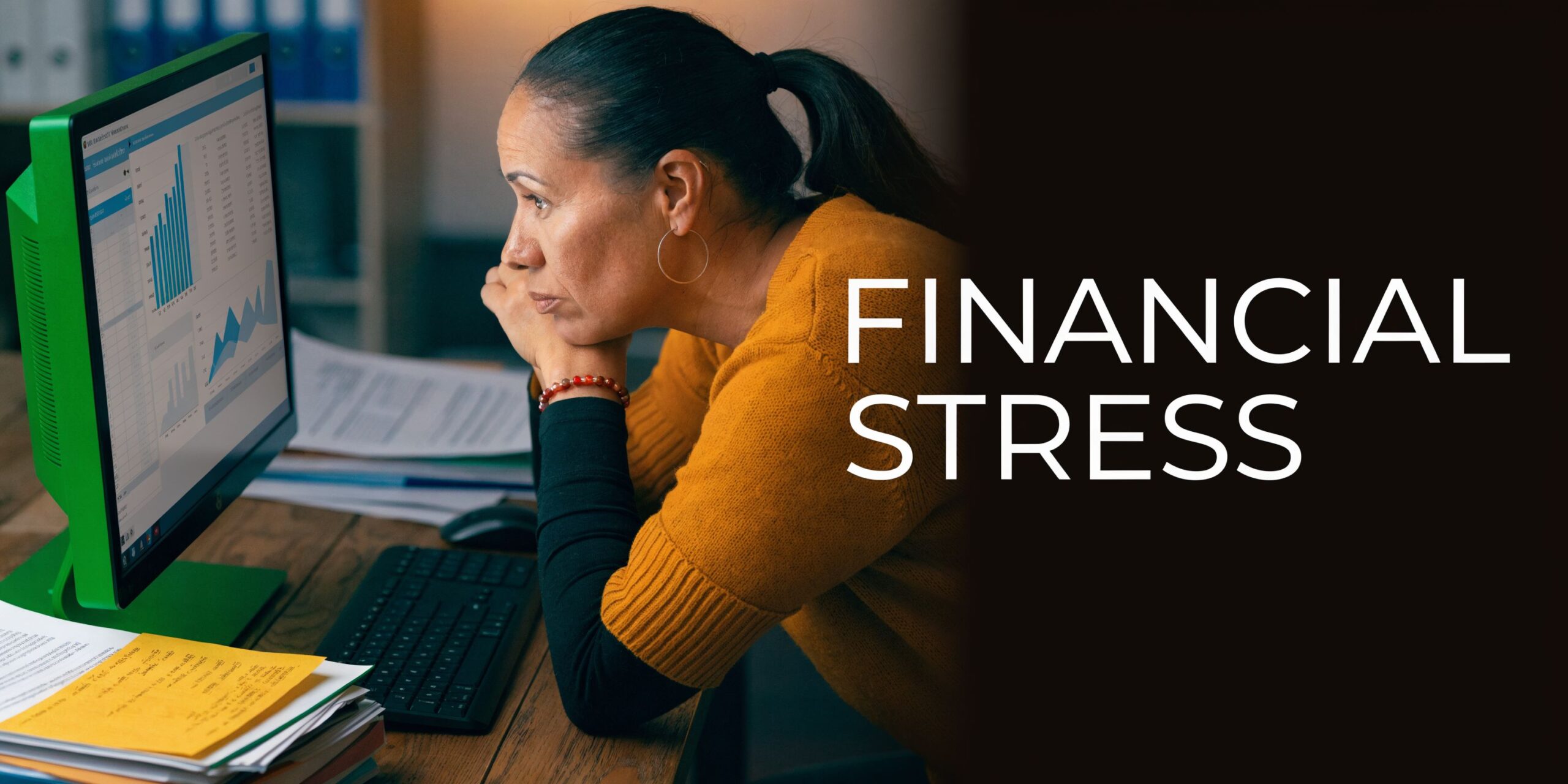 A focused woman looking at financial charts on a computer screen, experiencing stress while working at home.