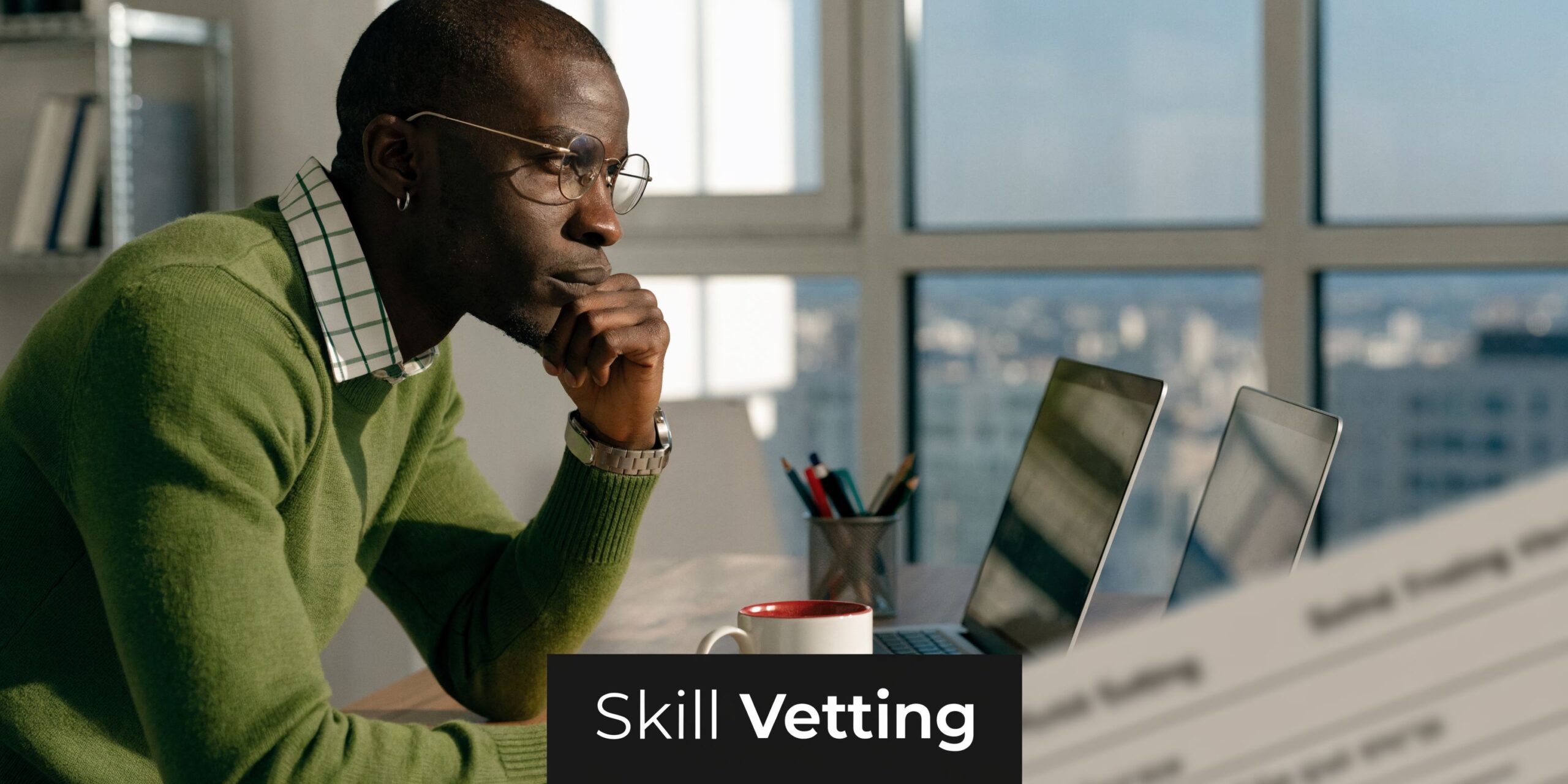 A focused professional in a green sweater thoughtfully reviewing business documents while working at a modern office desk.